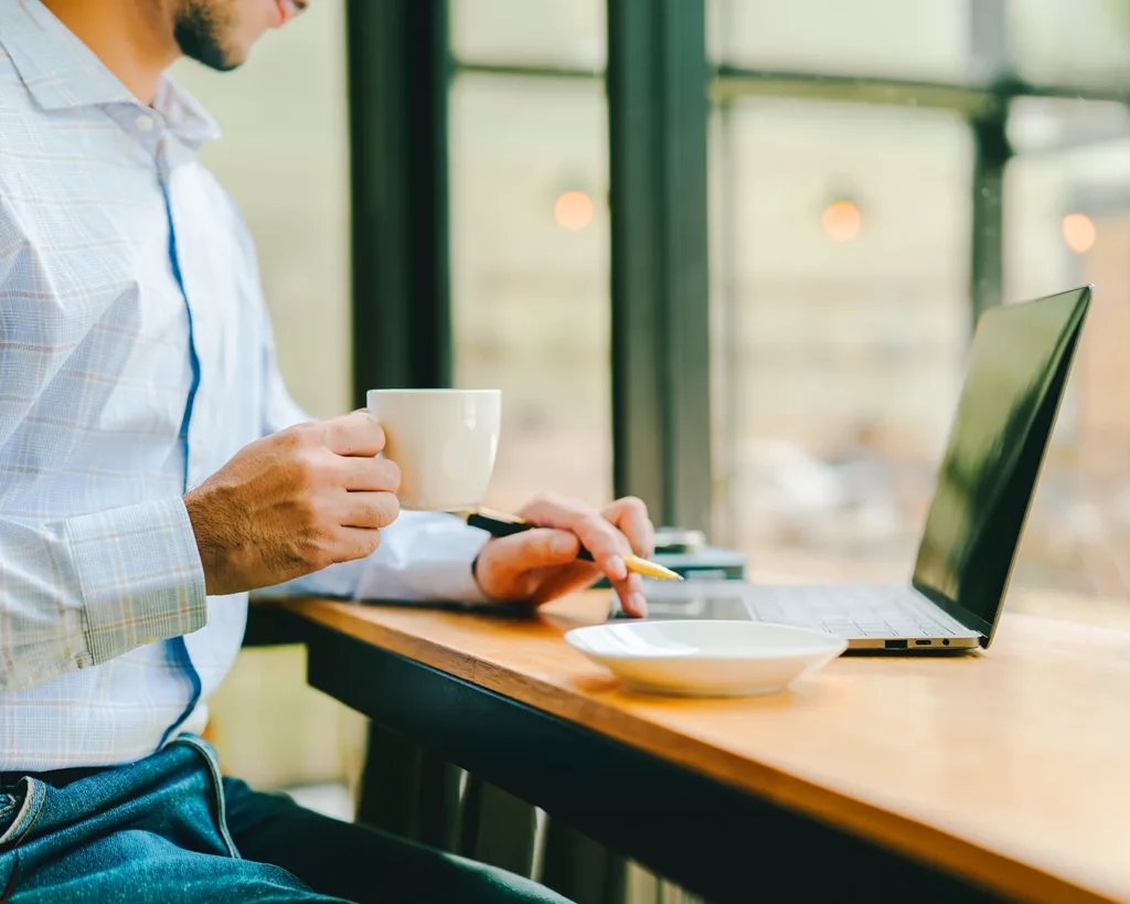 Professional working on a laptop in a café with coffee, illustrating restaurant website management, digital business planning, and online customer engagement.