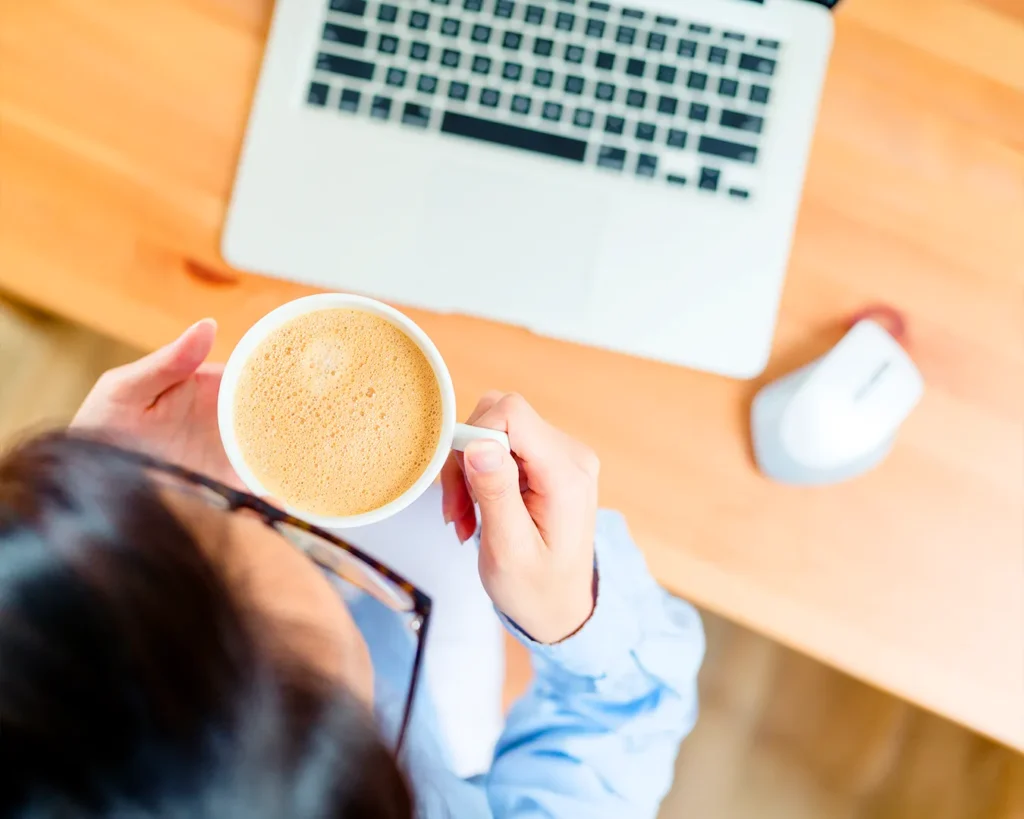 Coffee shop owner analyzing first-party customer data on laptop with coffee
