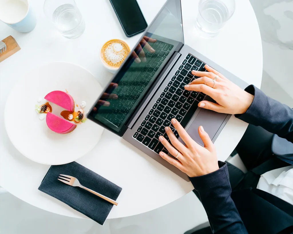 Restaurant manager analyzing first-party customer data with laptop during café service