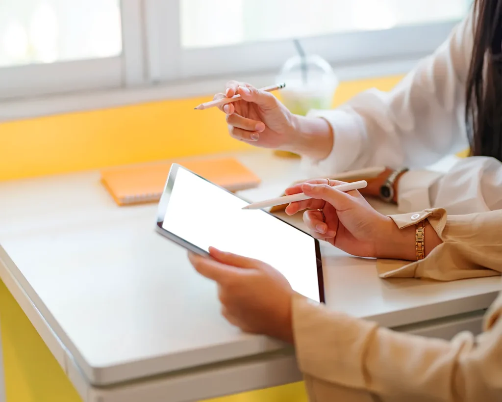 Team collaborating on a tablet during a digital strategy meeting, representing restaurant app planning, website development, and hospitality technology consultation.