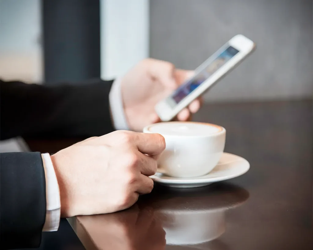 Business professional checking customer engagement metrics on smartphone over coffee