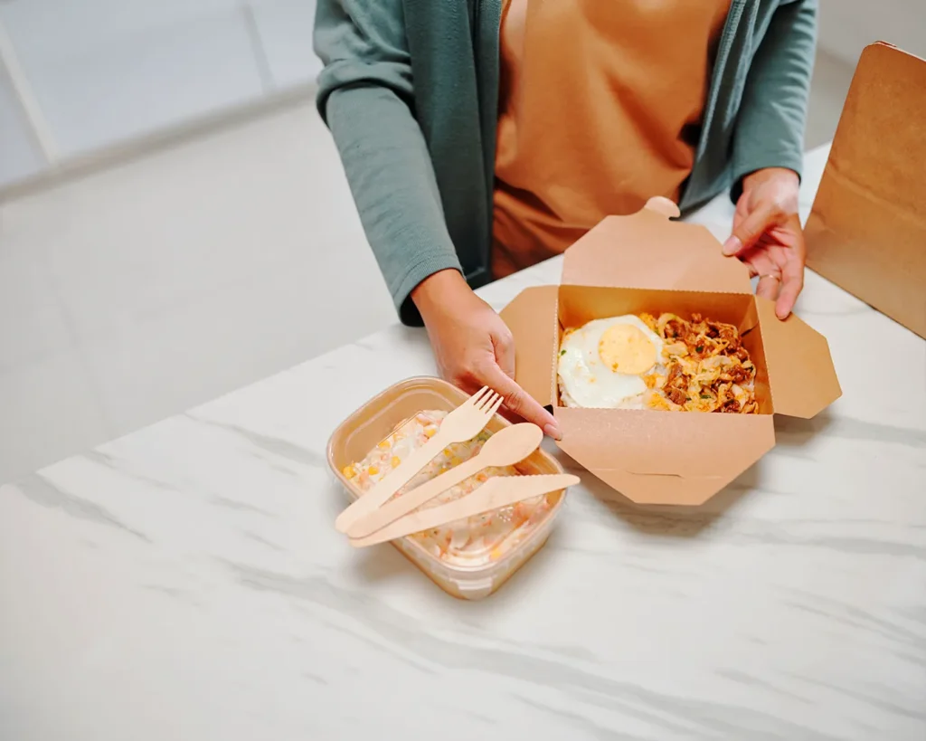 Customer unboxing takeaway meal in premium food packaging for positive delivery experience and customer advocacy