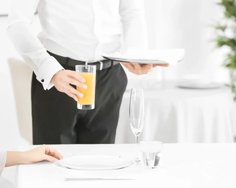 Restaurant server serving a drink and plated meal to guest