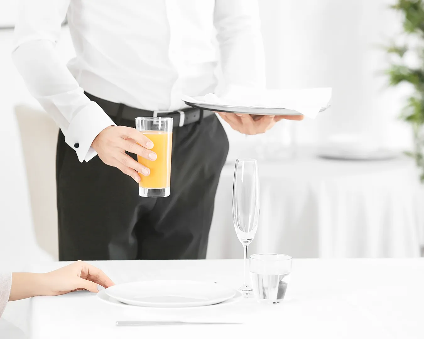 Restaurant server serving a drink and plated meal to guest
