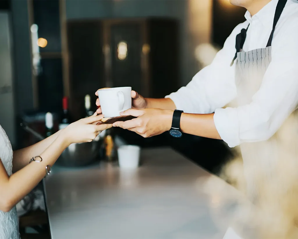 Restaurant staff handing coffee to satisfied customer during exceptional hospitality service