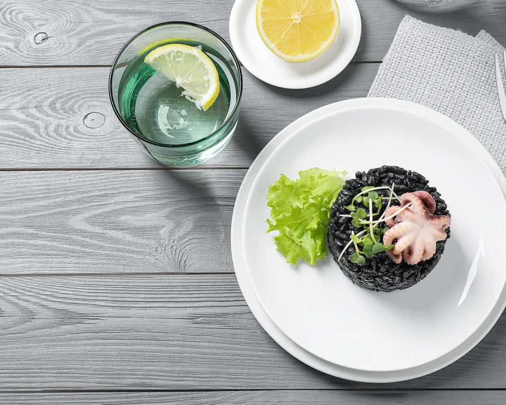 Gourmet restaurant dish with octopus and black rice served with lemon water