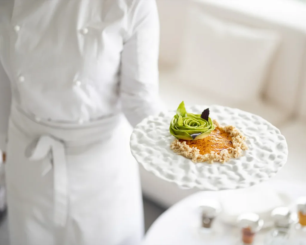 Fine dining restaurant server presenting beautifully plated gourmet dish to guest