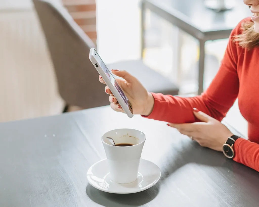 Restaurant customer browsing content on a tablet while enjoying coffee