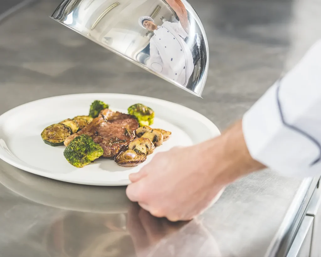 Chef presenting a gourmet dish in a restaurant kitchen