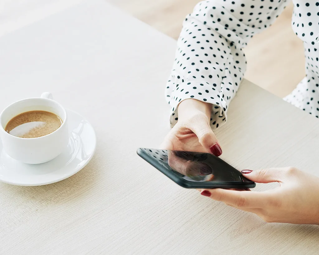 Customer browsing restaurant information on a smartphone beside a coffee, representing mobile search, online reservations, restaurant SEO, and Google Business Profile.