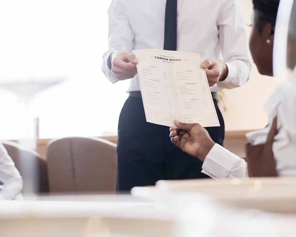 Restaurant waiter explaining menu options to diners