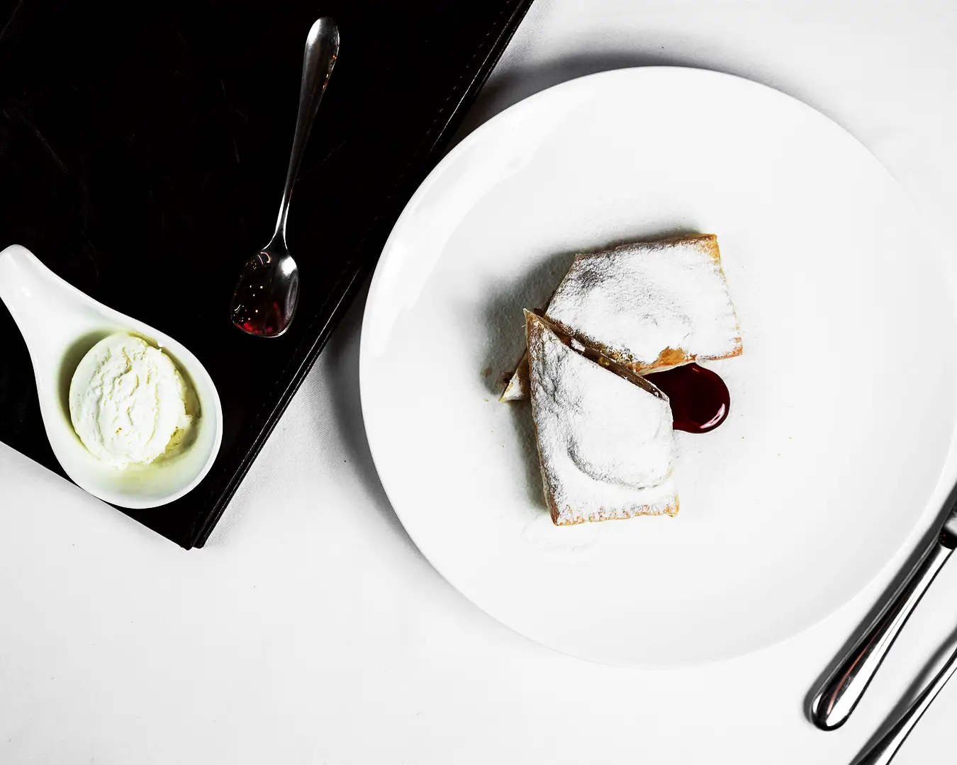 Fine dining dessert presentation with powdered pastry, ice cream, and elegant plating
