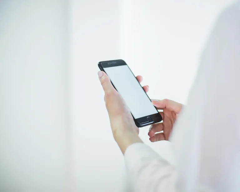 Customer using smartphone while dining at a restaurant, highlighting digital engagement and consistent guest experience
