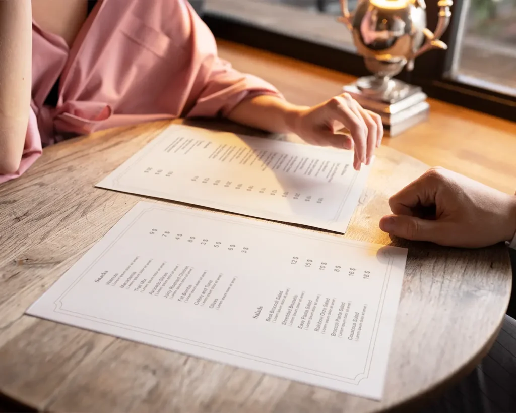 Restaurant customers reviewing menu prices and food selections at a dining table