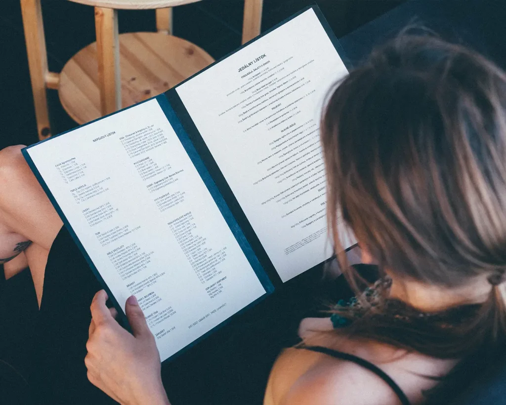 Diner reading a restaurant menu while choosing dishes and evaluating prices