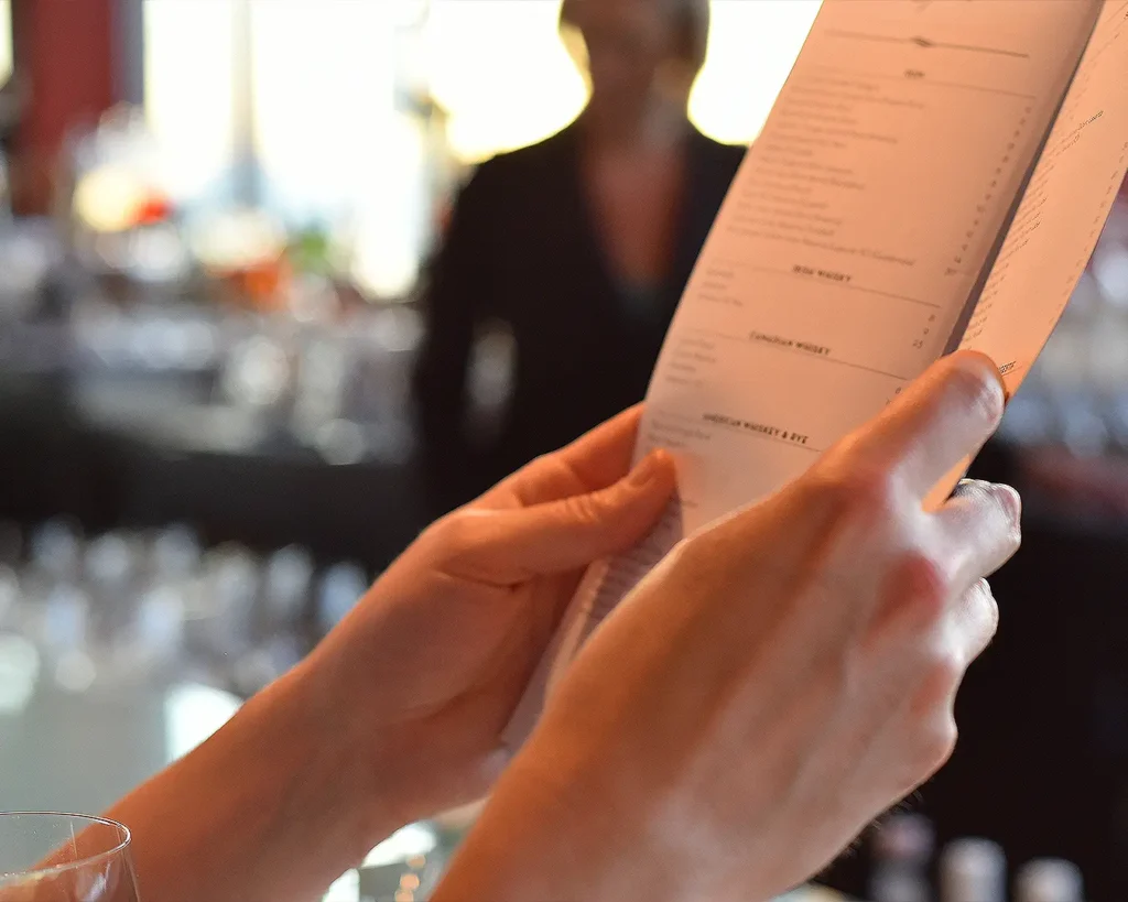 Customer reviewing a restaurant menu with food and beverage options in a modern dining setting