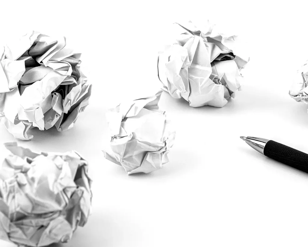 Crumpled paper and pen on a clean desk symbolising creative revisions, branding concepts, and the restaurant identity design process