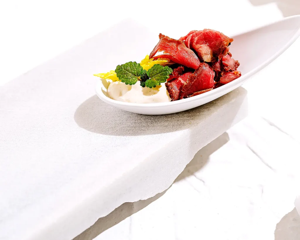 Minimal plated beef dish with fresh herbs showcasing refined restaurant food presentation and visual branding