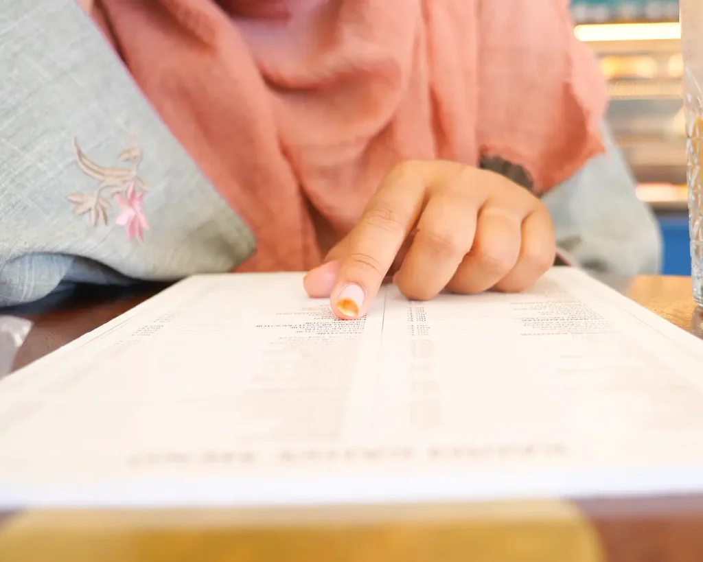 Customer reading a restaurant menu with clear typography and organized menu design